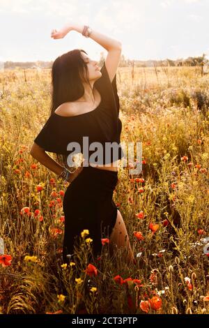 Junge schöne schlanke, fit Brünette Frau mit dunklen langen Haaren tanzen in schwarz lateinischen Stil Sommer schwarz Kleid Anzug off shoulders top und lange Rock Witz Stockfoto