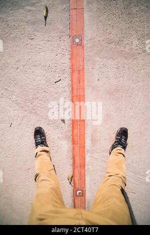 Ein Fuß auf beiden Seiten des Äquators in der "Weltmittelwelt", San Antonio de Pichincha, Quito, Ecuador, Südamerika Stockfoto