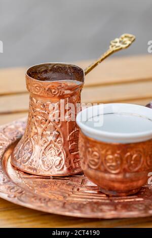 Traditioneller schwarzer bosnischer Kaffee in schöner Kupferkeuze am Holztisch Stockfoto