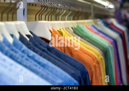 Helle bunte Baumwollhemden auf Kleiderbügel im Boutique-Shop schließen Nach oben Stockfoto