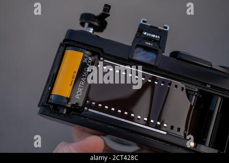 Eine Hand hält eine analoge SLR-Kamera mit geöffneter Rückseite und zeigt Kodak Portra 160 Farbfilm auf der Rückseite geladen. Stockfoto