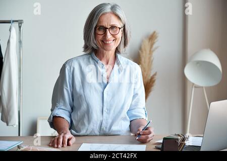 Glücklich mittleren Alters stilvolle Frau Modedesignerin am Arbeitsplatz, Porträt. Stockfoto