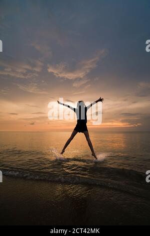 Eine junge Frau macht einen Sternsprung und genießt ihre Freiheit am Strand bei Sonnenuntergang., Thailändische Inseln auf Koh Samui, Thailand, Südostasien Stockfoto