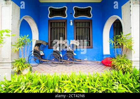 Rikschas gegen die Blue Walls des Cheong Fatt Tze Mansion, in George Town, Penang, Malaysia, Südostasien Stockfoto