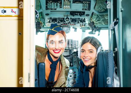 Schöne Frau Pilot trägt Uniform. Glücklicher und erfolgreicher Flug. Blick auf die Kamera in der Ebene. Mädchen, die die Kamera betrachten. Zwei Piloteninnen sitzen darin Stockfoto