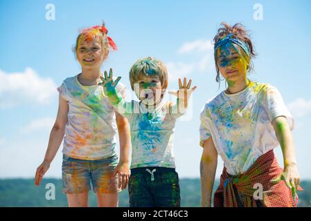 Fröhliche Kinder zeigen ihre Hände in hellen Farben gemalt. Bunte Gesichter, Farbspritzer, buntes Puder auf Kinderkörper. Stockfoto