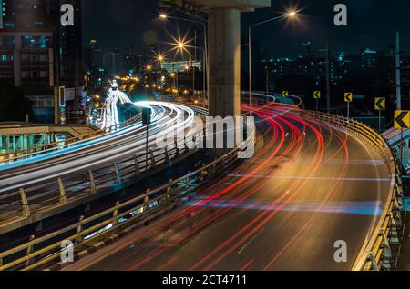 Überführung der Light Trails mit Bangkok City Hintergrund bei Nacht. Schöne Kurven. Selektiver Fokus. Stockfoto