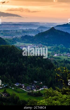 Typische slowenische Landschaft. Blick auf den nebligen Sonnenaufgang vom Osojnica-Hügel am Bleder See in Richtung Radovljica, Region Gorenjska, Slowenien, Europa Stockfoto