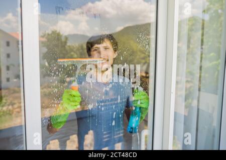 Ein junger Mann putzte das Fenster mit einem Fensterputzer Stockfoto
