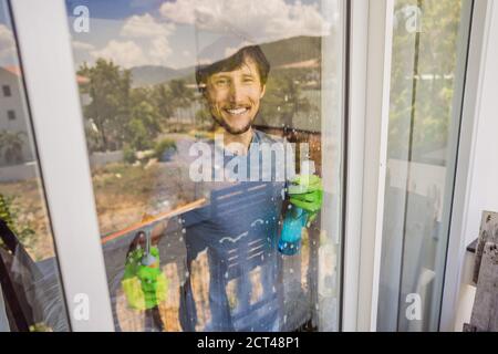 Ein junger Mann putzte das Fenster mit einem Fensterputzer Stockfoto