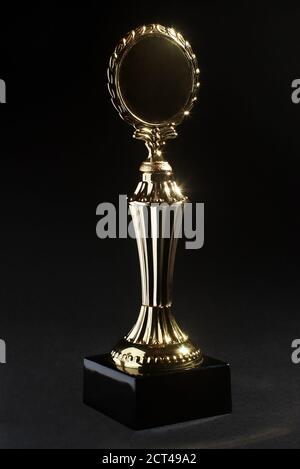 Goldene Trophäe mit Lorbeerkranz auf schwarzem Hintergrund Stockfoto