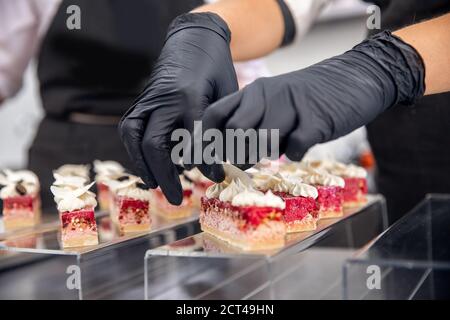 Chef Hand in Patisserie Restaurant bereitet Kuchen und dekoriert mit Schokoladeneisung Stockfoto