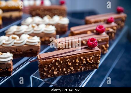 Catering-Tisch mit in Scheiben geschnittenen Schokoladenkuchen mit frischen Himbeeren dekoriert Und Muttern Stockfoto