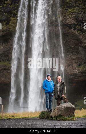 Vater und Sohn in Seljalandsfoss, einem berühmten Wasserfall direkt an der Route 1 in Südisland (Sudurland), Europa Stockfoto