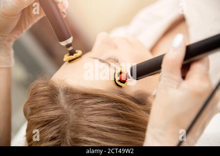 Frau bekommen Gesicht Hautpflege Verjüngung mit rf Lifting elektrisch Apparat professionellen Schönheitssalon Stockfoto