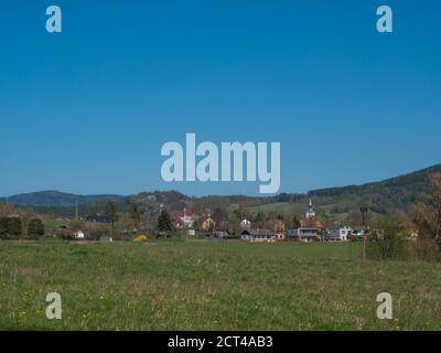 Frühlingslandschaft mit Blick auf das Dorf Cvikov in den Bergen von Lusitian mit alten und modernen Häusern und üppig grüner Wiese, Laub- und Fichtenbaum Stockfoto