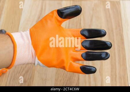 Orange Bauhandschuh in der Hand gekleidet, Holzhintergrund Stockfoto