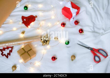 Weihnachtsgeschenke Verpackung, Papier, Schere und Accessoires auf weißem Bett Stockfoto