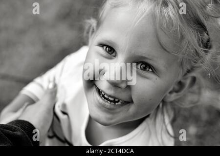 Nahaufnahme schwarz-weiß Porträt von niedlichen liebenswert lächelnd kaukasischen Kind. Porträt eines glücklichen Kindes in der Natur. Happy Childhood Konzept. Das Baby Stockfoto