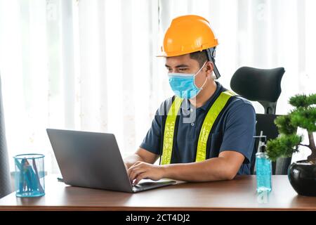 Quarantäne, asiatische Ingenieur trägt Gesicht schützende medizinische Maske zum Schutz vor Viruserkrankungen mit Laptop-Computer im Baubüro Stockfoto