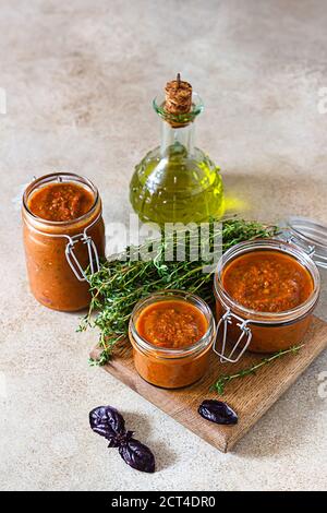 Köstlicher Gemüsekaviar in Gläsern, Thymian und purpurfarbenem Basilikum auf Holzbrett, heller Hintergrund. Hausgemachter Kaviar mit Auberginen, Tomaten und Paprika. Stockfoto