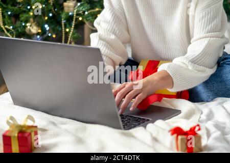 Weihnachten Online-Shopping. Mädchen macht Ordnung auf Laptop. Frau kaufen Geschenke, bereiten Sie zu Weihnachten, unter Geschenk-Boxen und Pakete. Winterurlaub Verkäufe. Stockfoto