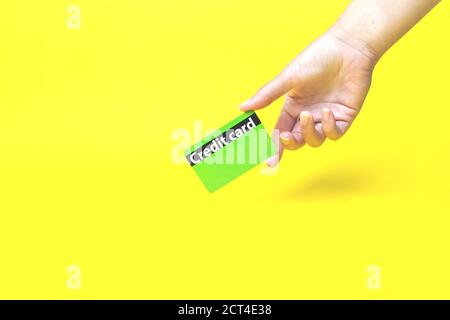 Hand hält eine Bankkarte auf gelbem Hintergrund Stockfoto