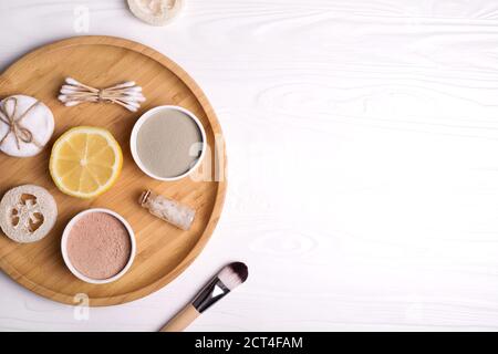 Kosmetische Ton Gesichtsmasken, Meersalz, Zitrone und Pinsel auf Holz Hintergrund. Stockfoto