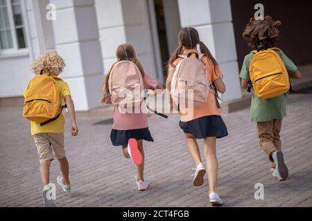 Schulkinder mit Rucksäcken gehen morgens zur Schule Stockfoto