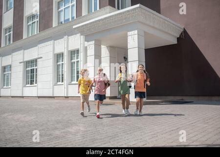 Schulkinder mit Rucksäcken verlassen die Schule nach dem Unterricht Stockfoto