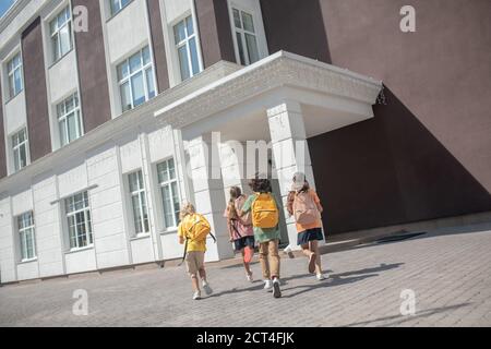 Kinder mit Rucksäcken spielen nach dem Unterricht auf dem Schulhof Stockfoto