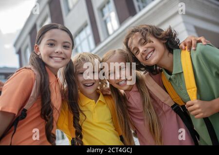 Schulkinder stehen auf dem Schulhof und sehen fröhlich aus Stockfoto