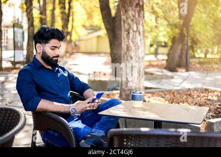 Junger erfolgreicher Geschäftsmann, der im Café im Freien arbeitet. Stockfoto