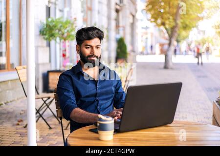 Junger erfolgreicher Geschäftsmann, der im Café im Freien arbeitet. Stockfoto