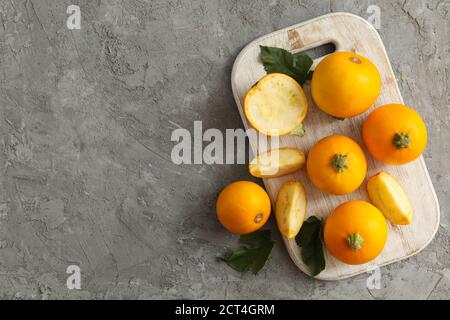 Brett mit runden Zucchini und Blättern auf grauem Hintergrund Stockfoto