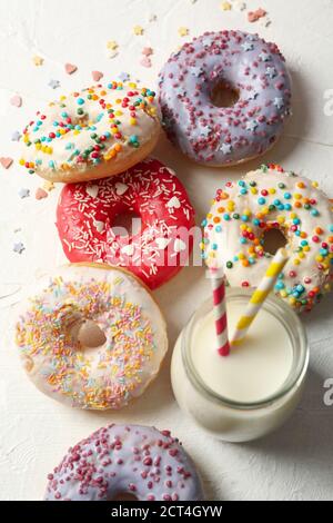 Milch und leckere Donuts auf weißem Hintergrund Stockfoto