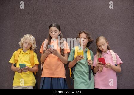 Vier Kinder spielen Online-Spiele auf ihren Smartphones Stockfoto