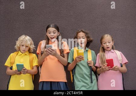 Vier Kinder spielen Online-Spiele auf ihren Smartphones und suchen Beteiligt Stockfoto