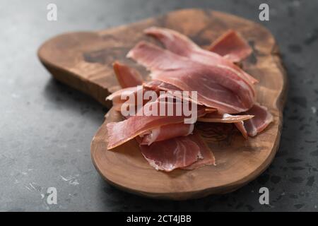 Geschnittener parmaschinken auf Olivenholzplatte, flacher Fokus Stockfoto