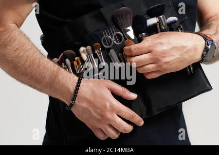 Professionelle Make-up Artist mit Gürteltasche mit Make-up Pinsel. Stylist bei der Arbeit. Stockfoto