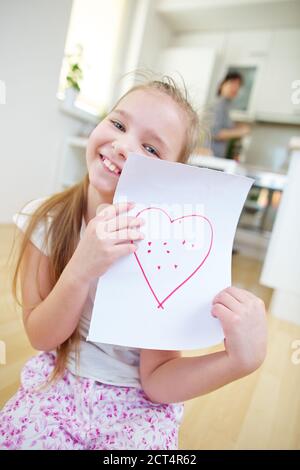 Happy girl zeigt ein Blatt Papier mit einem roten Herz Stockfoto