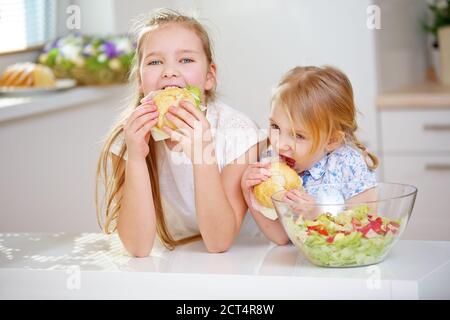 Zwei Kinder essen Sandwiches zum Frühstück in der Küche Stockfoto