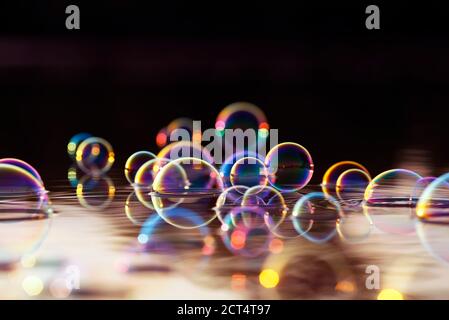 Schöne bunte Hintergrund mit glänzenden Seifenblasen fliegen über die Wasser und reflektiert in den Strahlen des Sonnenuntergangs Stockfoto