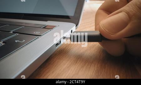 Nahaufnahme Makro-Aufnahme: Laptop auf dem Schreibtisch, Person fügt USB-C-Kabel-Adapter in Computer-Port. Stockfoto