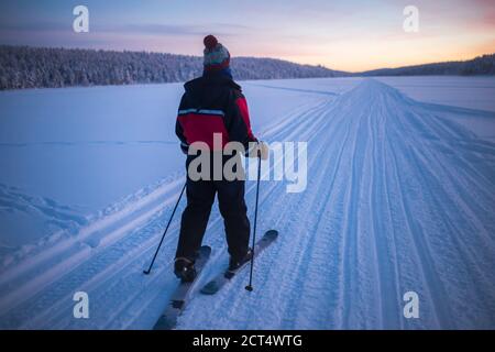 Skifahren auf dem gefrorenen See bei Torassieppi bei Sonnenuntergang, Lappland, Finnland Stockfoto