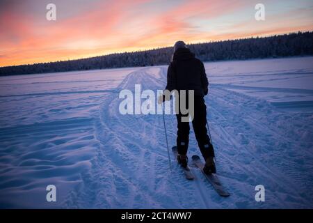 Skifahren auf dem gefrorenen See bei Torassieppi bei Sonnenuntergang, Lappland, Finnland Stockfoto