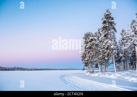 Gefrorener schneebedeckter See in der Winterlandschaft in Lappland Bei Sonnenuntergang im Polarkreis in Finnland Stockfoto
