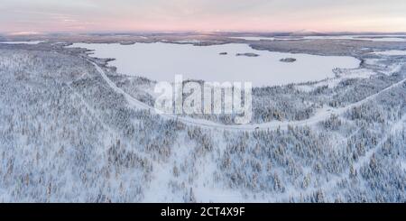 Luftaufnahme von schneebedeckten See und Wald Winterlandschaft zeigt Erstaunliche Lappland Landschaft in Skandinavien in Finnland Drohne Stockfoto