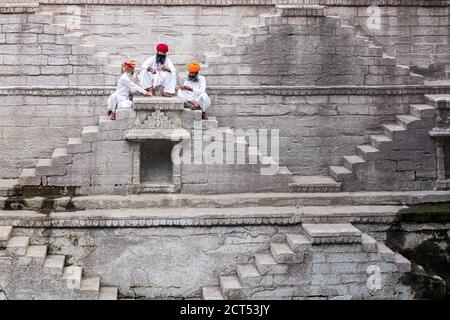 Drei Männer spielen Karten auf den Stufen der stepwell Toorji Ka Jhalra in Jodhpur, Rajasthan, Indien Stockfoto