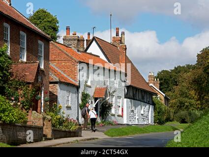 Ein Paar mittleren Alters, das am alten Postamt im Dorf South Dalton, East Yorkshire, England, vorbeigeht Stockfoto